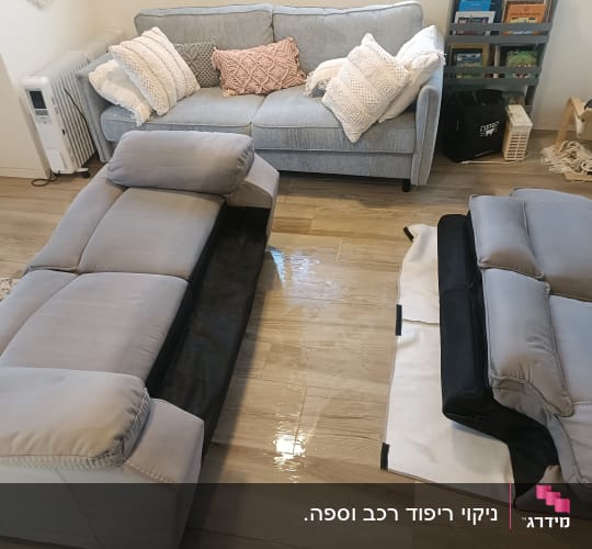 ספות בד אפורות מפורקות במהלך תהליך ניקוי בבית הלקוח